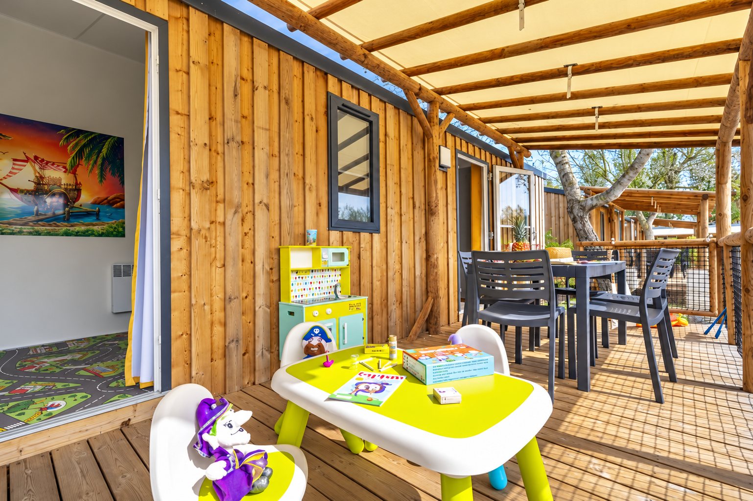 Mobil-home en bois avec terrasse au camping Fleur de Camargue : terrasse couverte avec coin jeux pour enfants et salon de jardin.